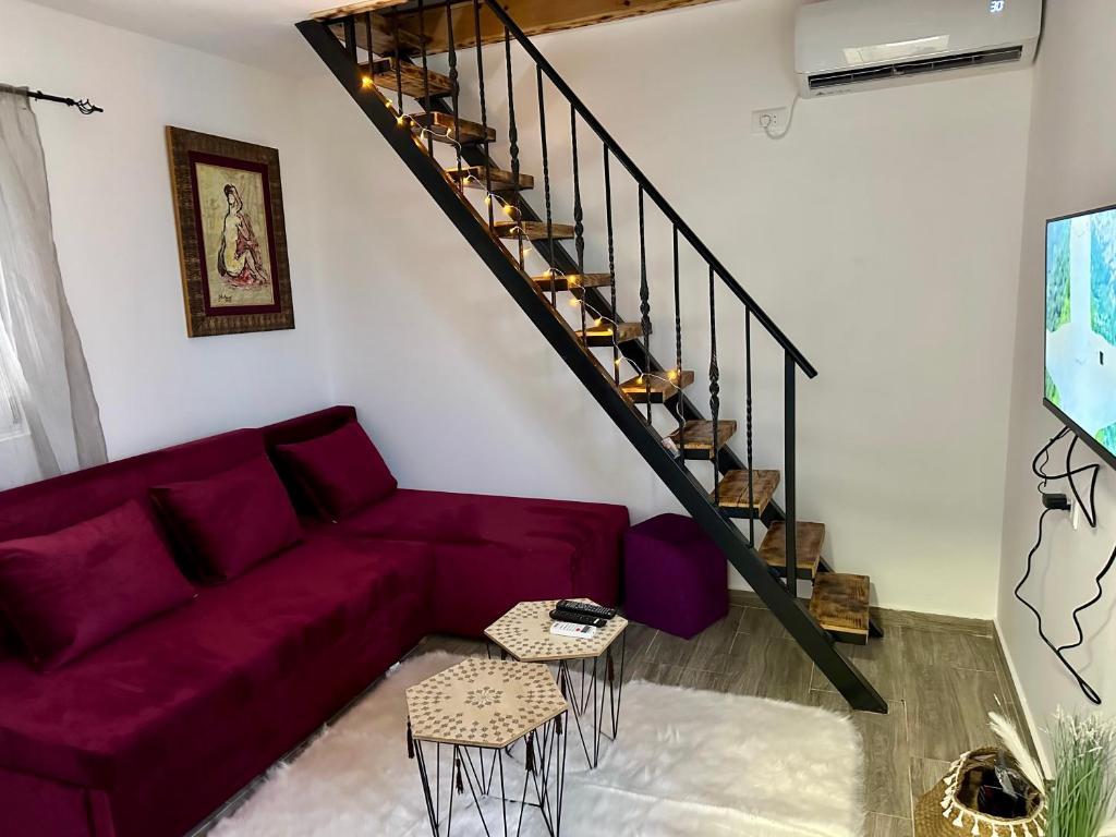 sala de estar con sofá púrpura y escaleras en Apartman2, en Podgorica