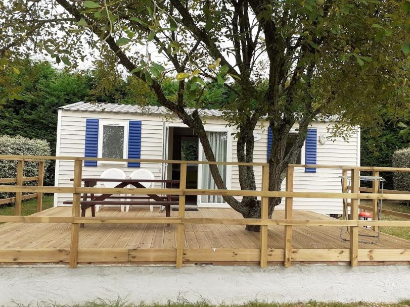 Les Mobile home de KERROYAL في Garlan: سطح خشبي مع مقعد وشجرة