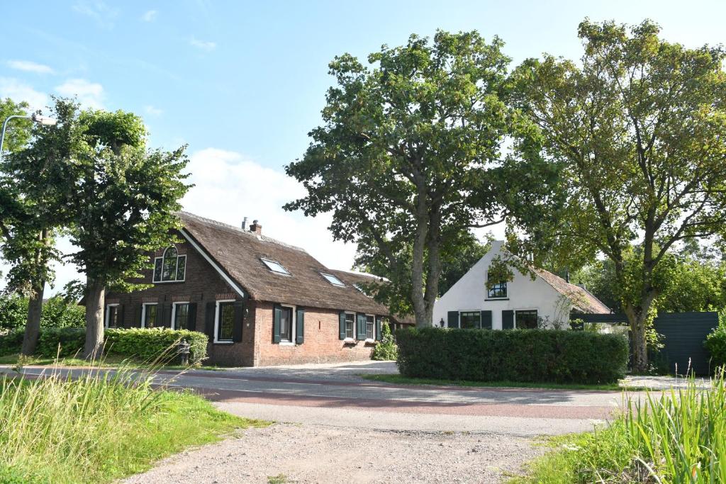 una casa de ladrillo con árboles delante de ella en Farmhouse, Jacuzzi, Sauna, BBQ grill & Garden, Sleeps 24, en Kockengen