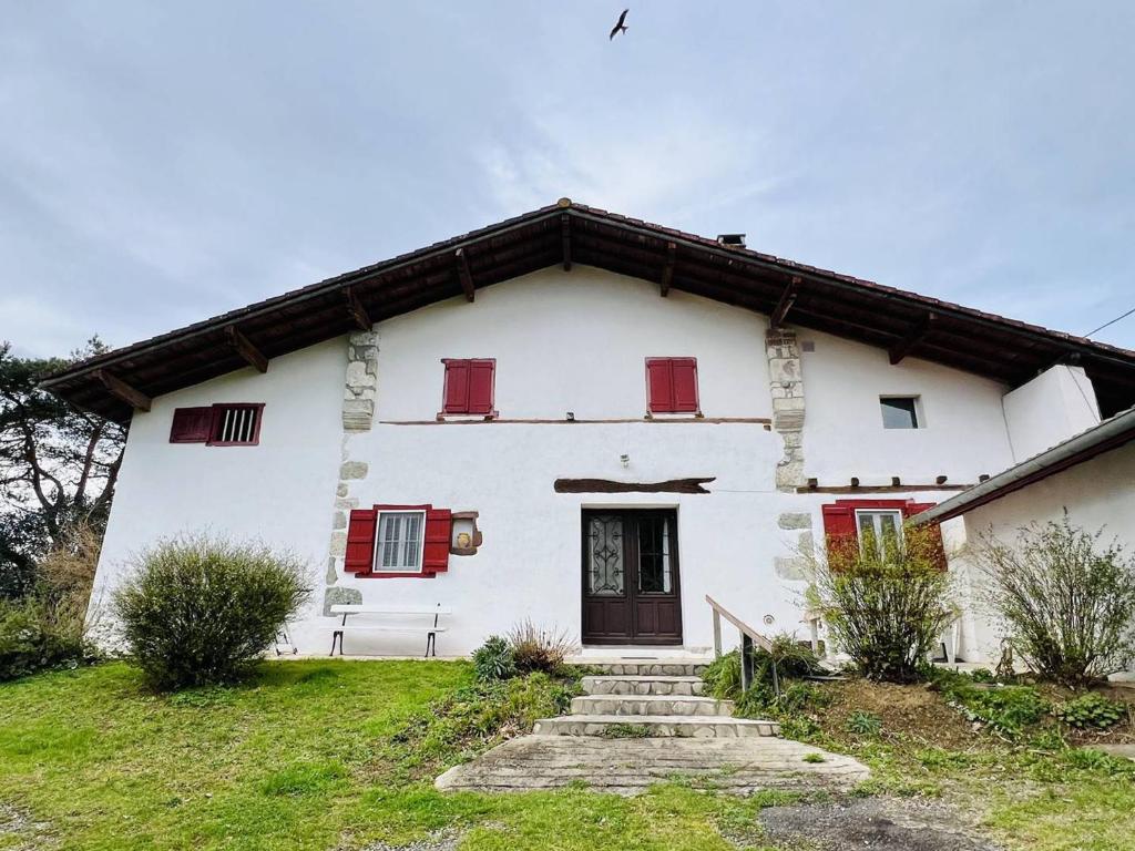 uma grande casa branca com janelas com persianas vermelhas em Maison Louhossoa, 4 pièces, 6 personnes - FR-1-495-134 em Louhossoa