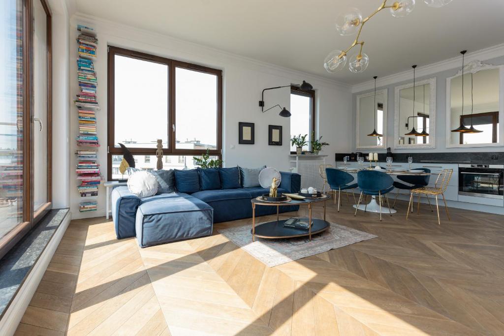 a living room with a blue couch and a kitchen at Royal Garden Apartment in Wilanow by Renters Prestige in Warsaw
