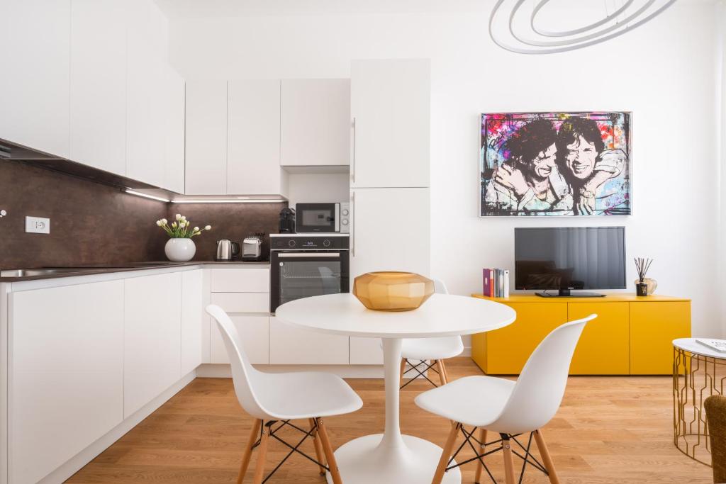 ミラノにあるSan Babila Design Apartment R&Rの白いキャビネット、白いテーブルと椅子付きのキッチン