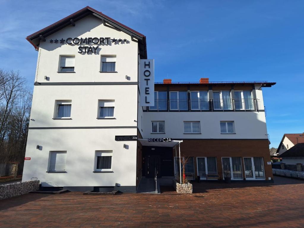 a white building with a sign on the front of it at Comfort Stay, EV, Parking in Bolesławiec