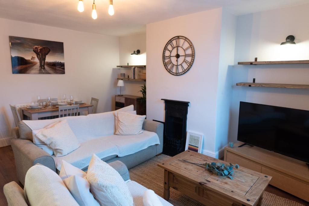 a living room with a couch and a clock on the wall at Oak Cottage in Deepcar