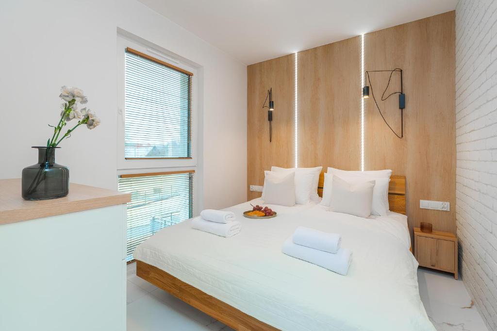 Schlafzimmer mit einem weißen Bett mit einem Kopfteil aus Holz in der Unterkunft Flatbook Apartamenty - Jantar Resort in Jantar