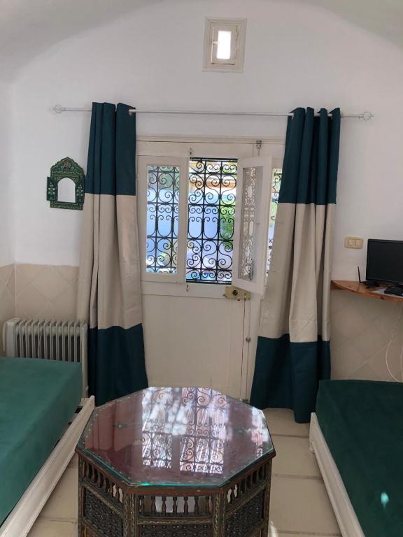 a living room with a table and a window at RESIDENCE DAR YASMINa in Mezraya