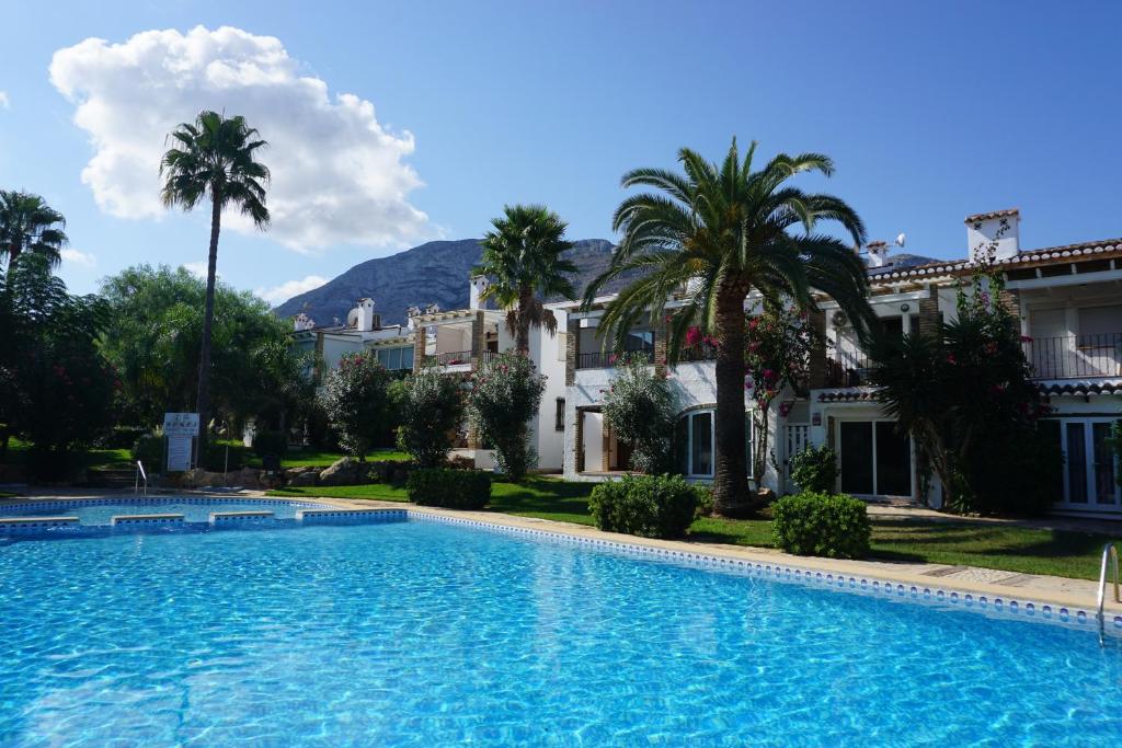 a swimming pool in front of a house with palm trees at Floridasol in Denia