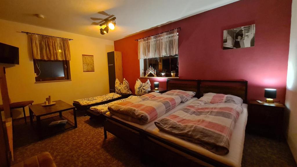 a bedroom with two beds and a red wall at Ferienwohnung Lippmann in Dorfchemnitz