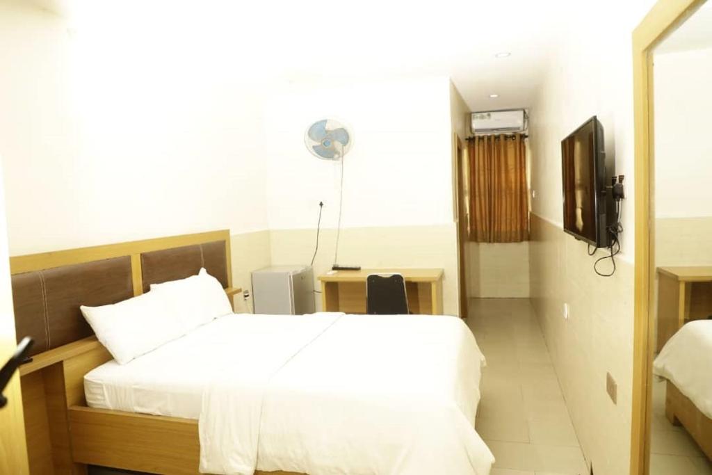 Habitación de hotel con cama y TV en CALBERT LODGE en Abuja