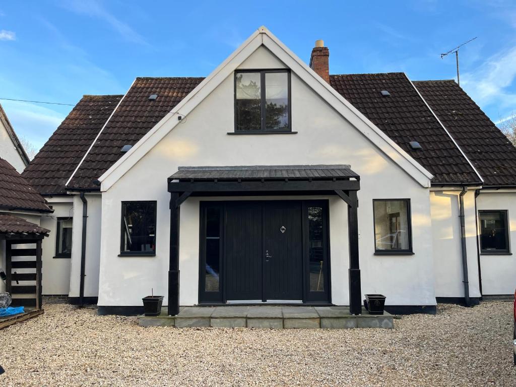 a white house with a black door at 8-10 Bed, Spacious House in Cheltenham