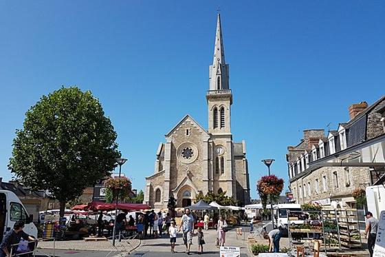 Une église avec une tour avec une horloge. dans l'établissement Maison de ville, à Broons