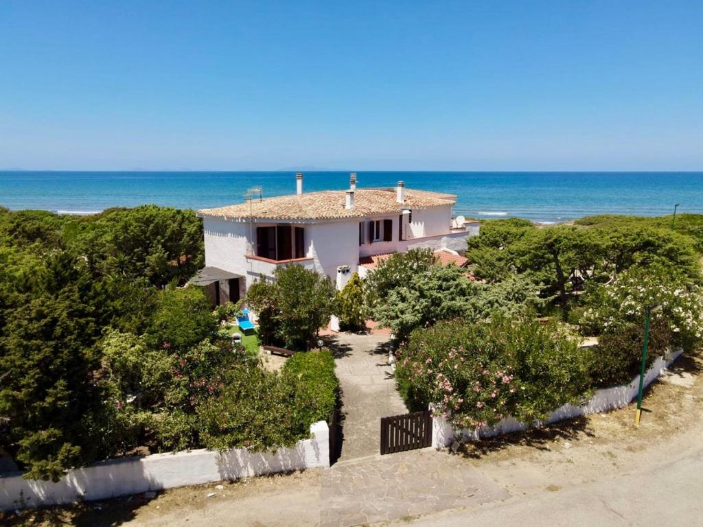 une maison sur la plage avec l'océan en arrière-plan dans l'établissement Villa i Ginepri. A pochi passi dal mare., à Marina di Sorso