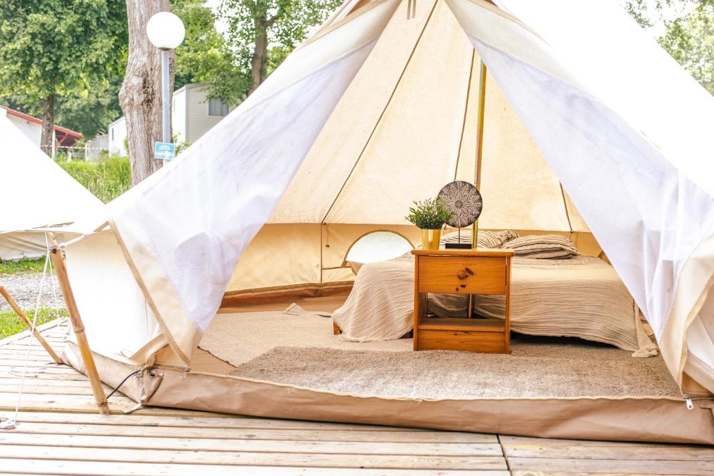 uma cama numa tenda com mesa de cabeceira em The Spot - 200m de la Plage em Saint-Hilaire-de-Riez