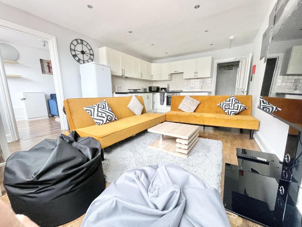 un soggiorno con divano giallo e una cucina di MUST VIEW - Slick Retreat in Holloway - Next to Emirates Stadium - Sleeps up to 6 a Londra