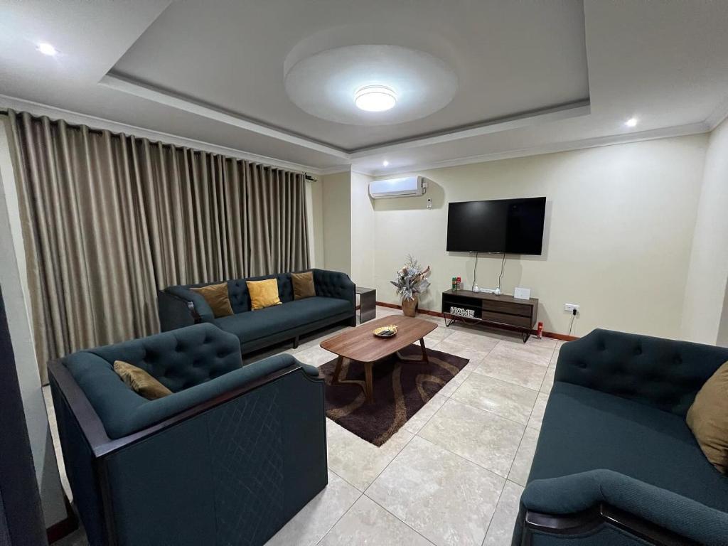 - un salon avec deux canapés bleus et une télévision dans l'établissement Roma Apartments, à Lusaka