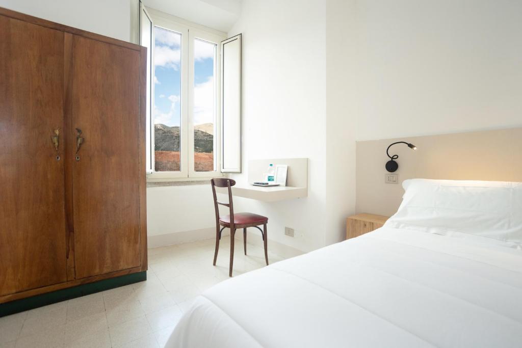 a bedroom with a bed and a chair and a window at Hotel Leon D'Oro in Alfedena