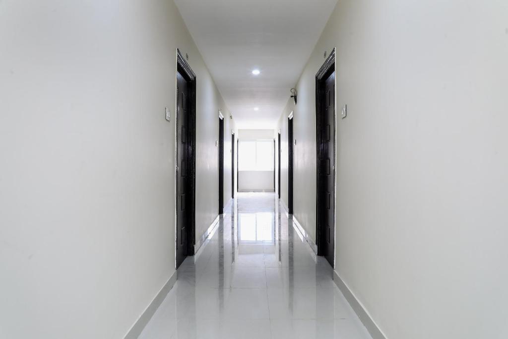 an empty corridor with white walls and black doors at OYO Way Inn in Kondapur