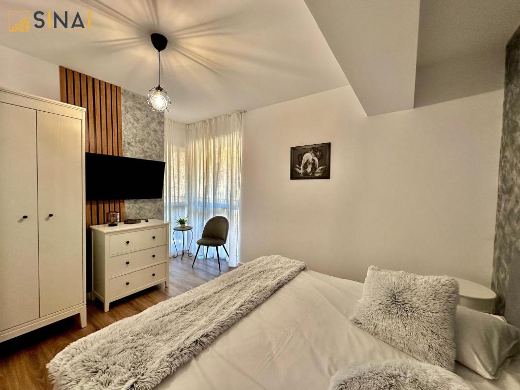 a bedroom with a bed and a dresser and a chair at SINAI APH Apartments in Sinaia