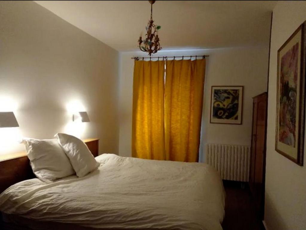 1 dormitorio con cama y cortina amarilla en La Maison Pain d'Epices, en Chichilianne