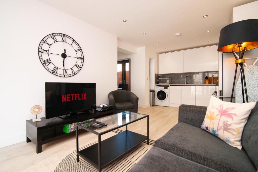 a living room with a couch and a clock on the wall at Spacious Luxury 2 Bedroom House in Derby