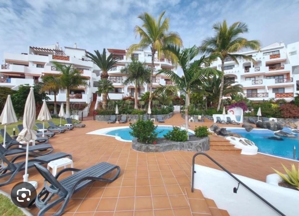 ein Resort mit einem Pool und Palmen in der Unterkunft SUL MARE in Puerto de Santiago