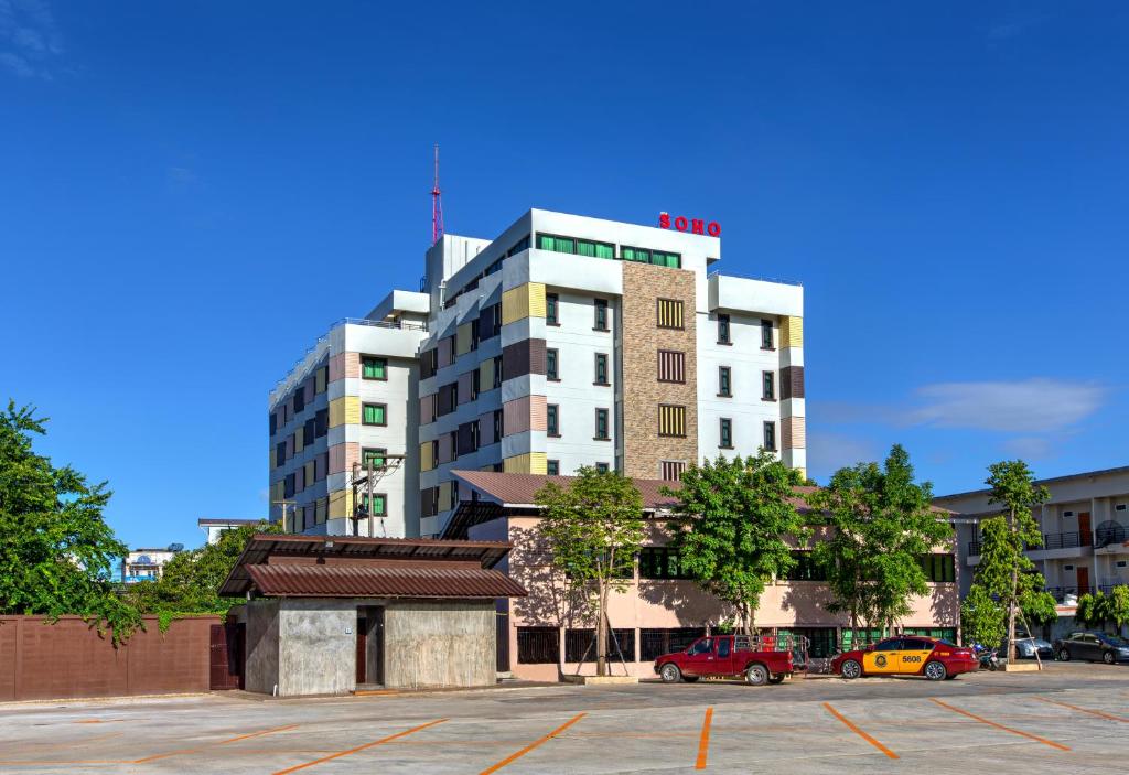 un edificio alto con coches estacionados en un estacionamiento en SOHO Boutique Hotel, en Tak