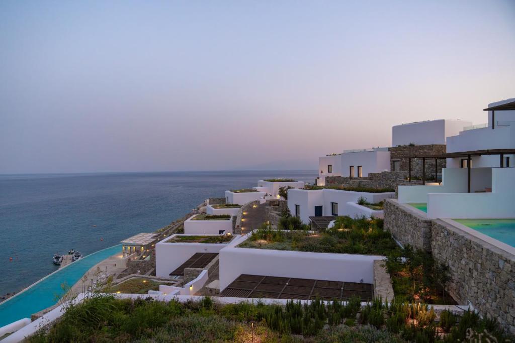 a row of white buildings next to the ocean at Cali Mykonos in Kalafatis