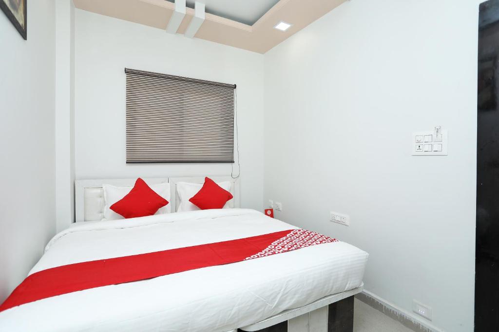 a red and white bed in a white room at Collection O Kolar Hotel in Bhopal