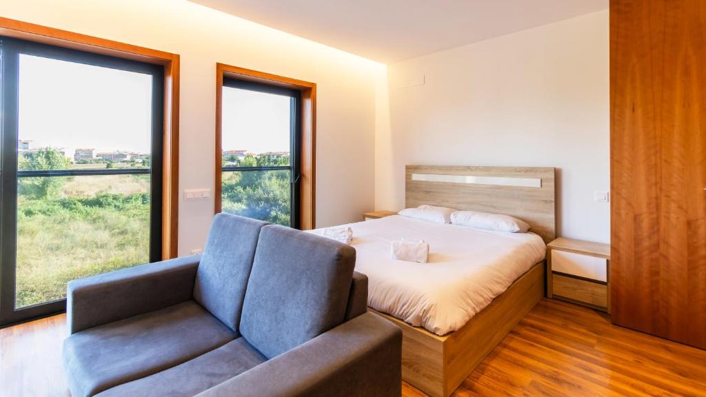 een slaapkamer met een bed, een bank en ramen bij Cute Asprela Apartment by Unique Hosts in Porto