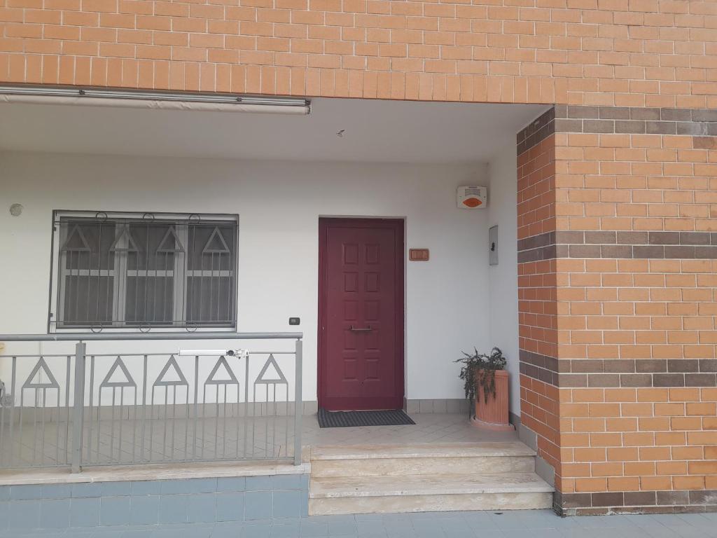 a brick building with a red door and a brick wall at Marica's Apartment in Gallinaro