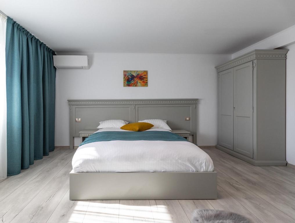 una camera da letto con un letto bianco con tende verdi di Sky Rooms by Volo Guest House a Sub Coastă