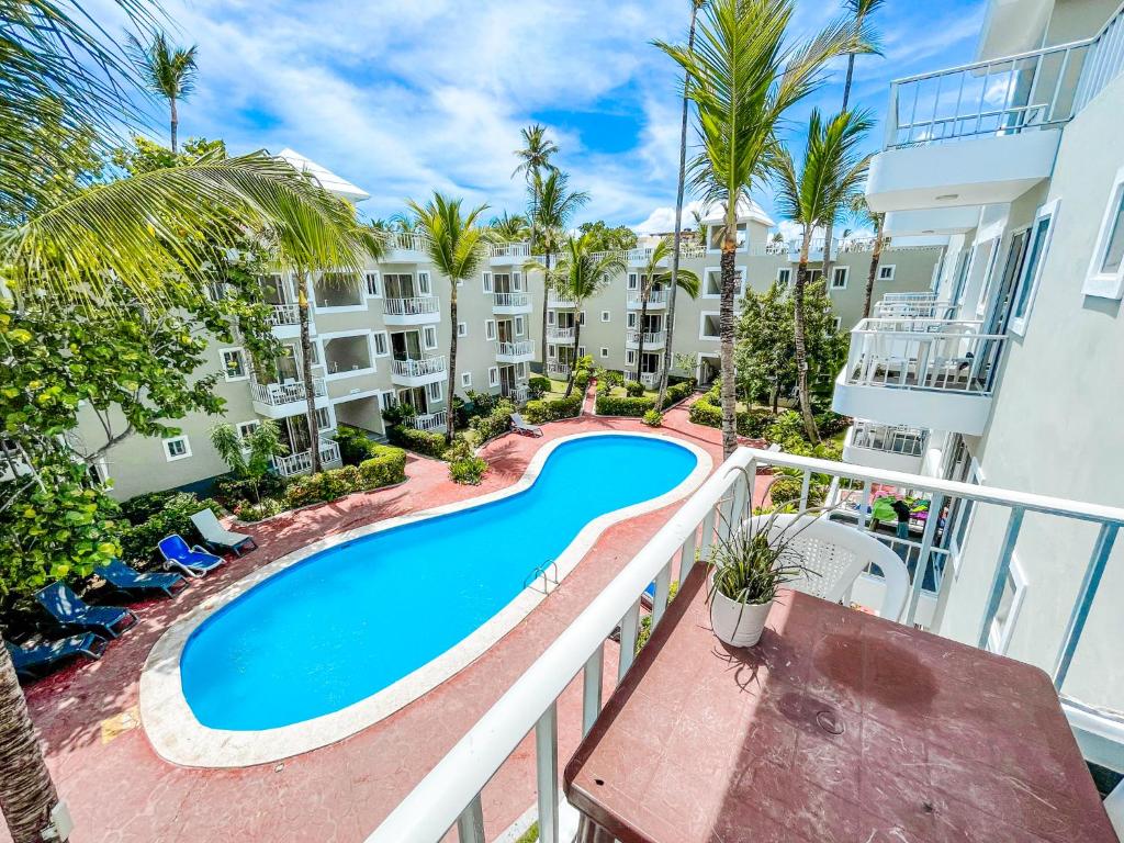an apartment balcony with a swimming pool and palm trees at TROPICAL ADVENTURE Sol Caribe STUDIOS SUITES Beach CLUB & SPA in Punta Cana