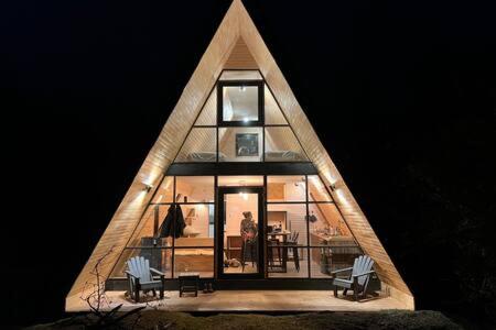 a house with a triangular roof with chairs and a table at OUTSCAPE l Cabaña Familiar en mejor sector de Cerro Castillo in Villa Cerro Castillo