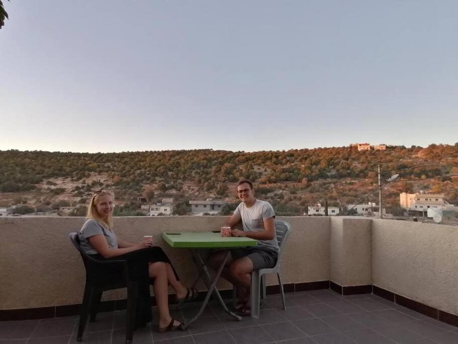 un uomo e una donna seduti a un tavolo su un balcone di Rural house البيت الريفي a Ajloun