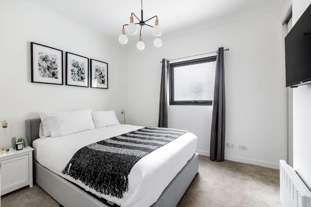 a white bedroom with a bed and a window at 'Flinders Lane Flair' Compact City-centre Comforts in Melbourne