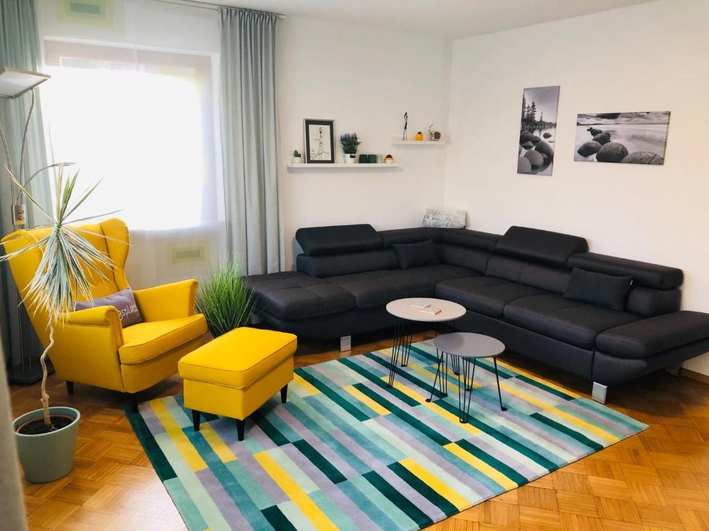 a living room with a black couch and yellow chairs at Ferienwohnung Zugvogel in Muhr amSee