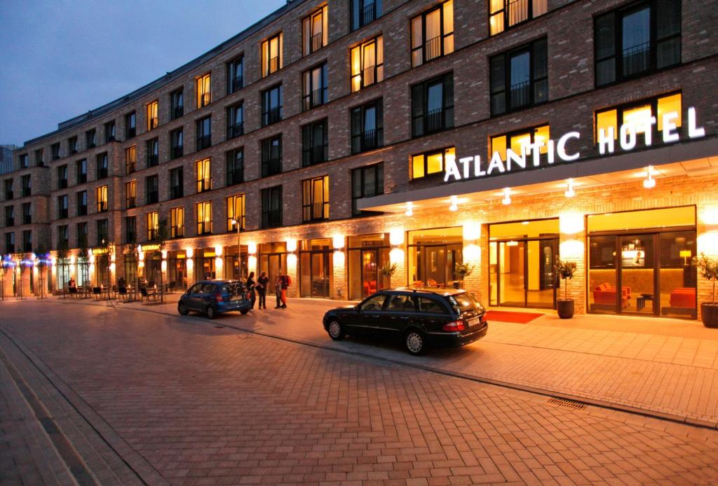 dos coches estacionados frente a un edificio en Atlantic Hotel Lübeck, en Lübeck