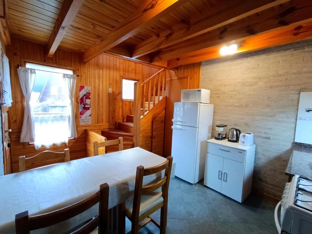 une cuisine avec une table et un réfrigérateur blanc dans l'établissement Cabañas del Arroyo, à San Martín de los Andes