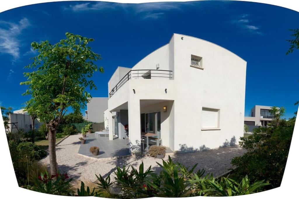 une maison blanche avec un arbre devant dans l'établissement Villa St louis à 50m de la mer+6 velos +Piscine+climatisation, à Sète