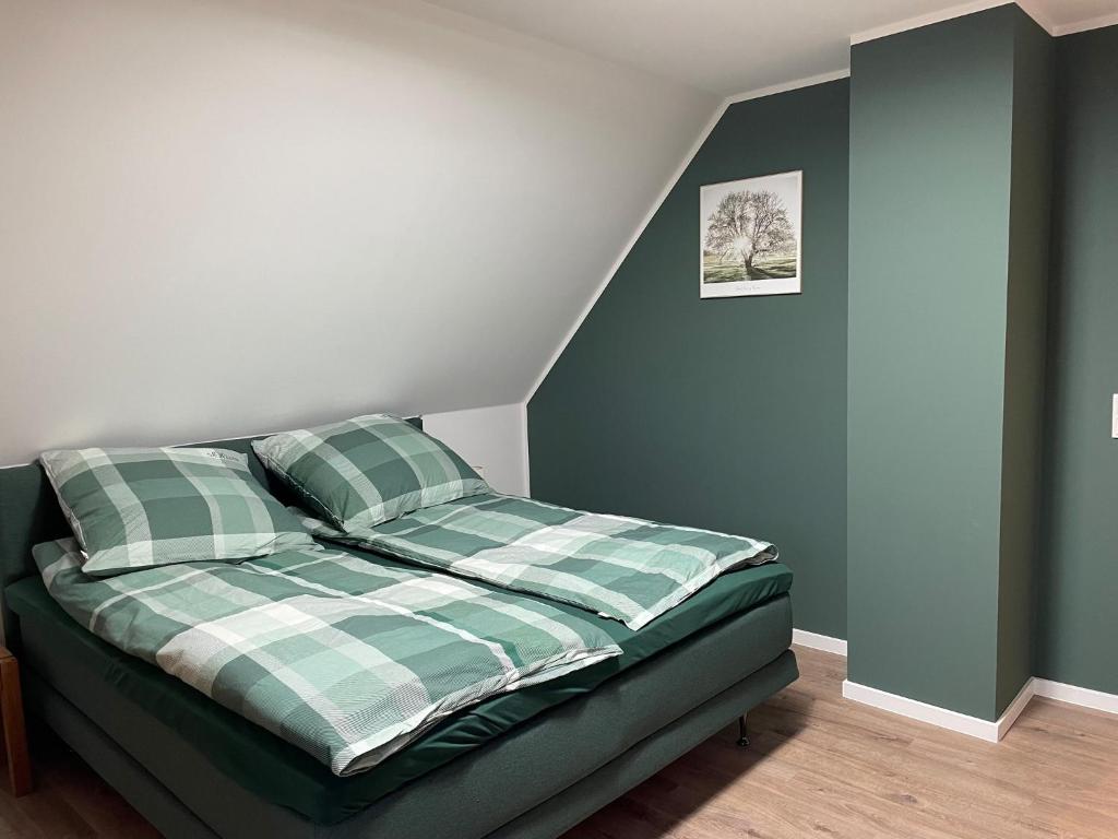 1 dormitorio con 1 cama con almohadas verdes y blancas en Fewo Haus Peters "De Lütte", en Marschkamp
