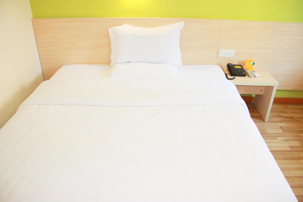 a large white bed in a room with a desk at 7Days Inn Heze Juancheng Bus Station in Juancheng