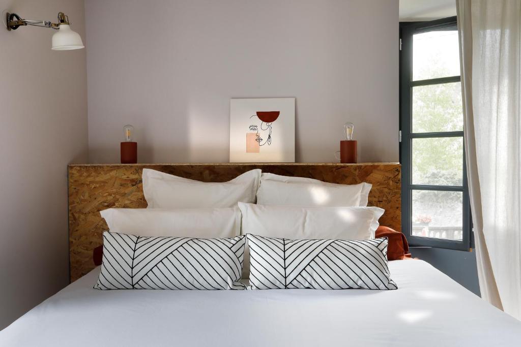a bedroom with a bed with white sheets and pillows at Maison Lavillete in Bielle
