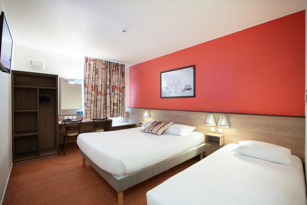 um quarto de hotel com duas camas e uma parede vermelha em Ace Hôtel Paris Marne La Vallée em Bailly-Romainvilliers