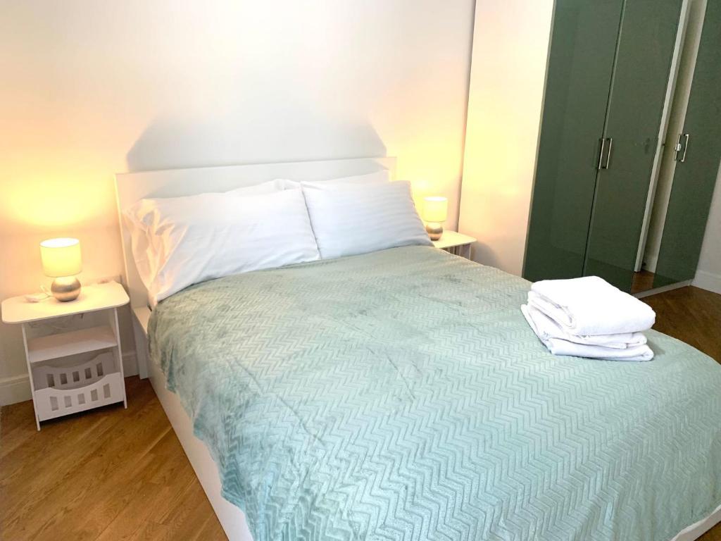 a bedroom with a bed with two lamps and towels on it at Dagenham 1 bed flat with views in Goodmayes