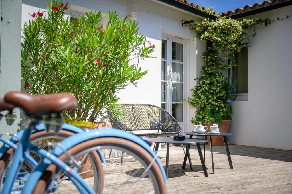 a bike parked in front of a house with plants at Hotel Le Clocher in Ars-en-Ré