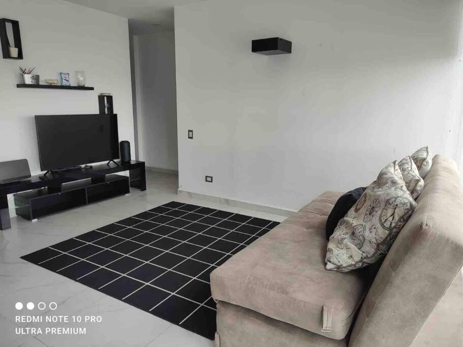 Nuevo departamento en Sonata, Blank, Lomas, puebla في Lomas de Angelopolis: غرفة معيشة مع أريكة وتلفزيون بشاشة مسطحة