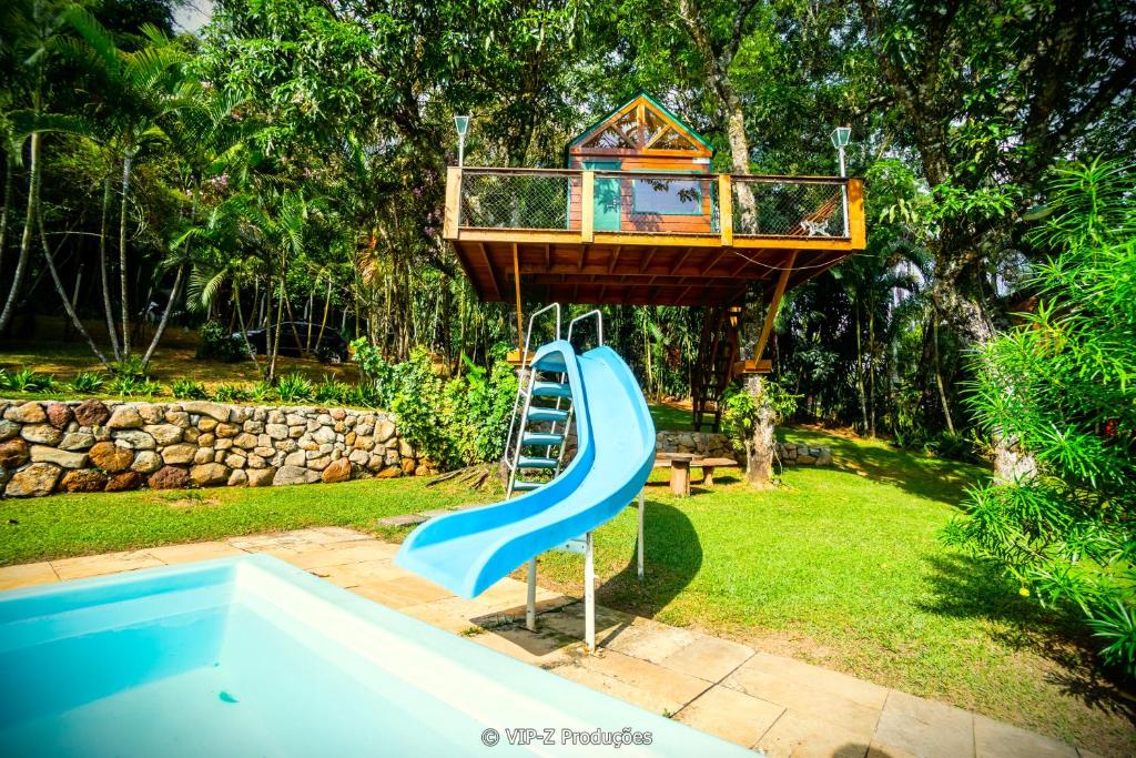 une maison de jeux pour enfants sur un toboggan à côté d'une piscine dans l'établissement Chácara Atibaia com Casa na Árvore, à Atibaia