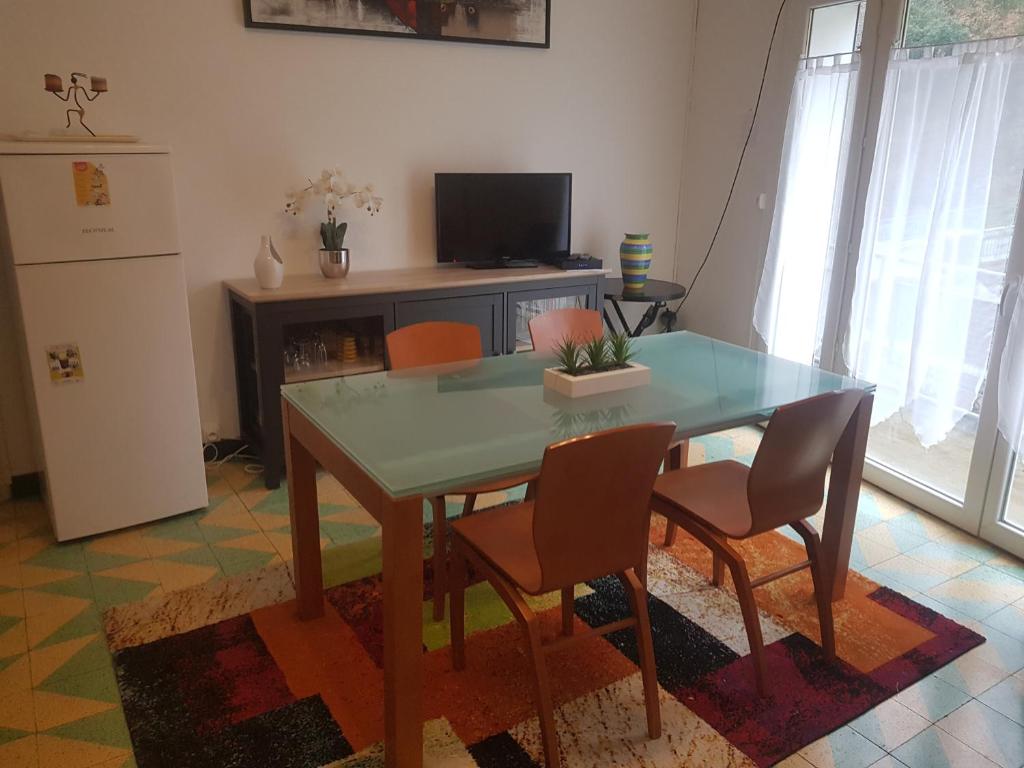 d'une salle à manger avec une table, des chaises et un réfrigérateur. dans l'établissement Les Pieds dans l'eau, à Avène