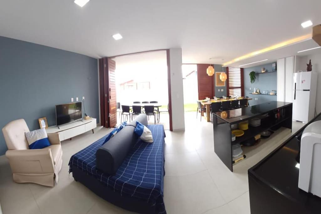 a living room with a blue couch and a kitchen at Casa em condomínio de Cotovelo c/ vista para o mar in Parnamirim