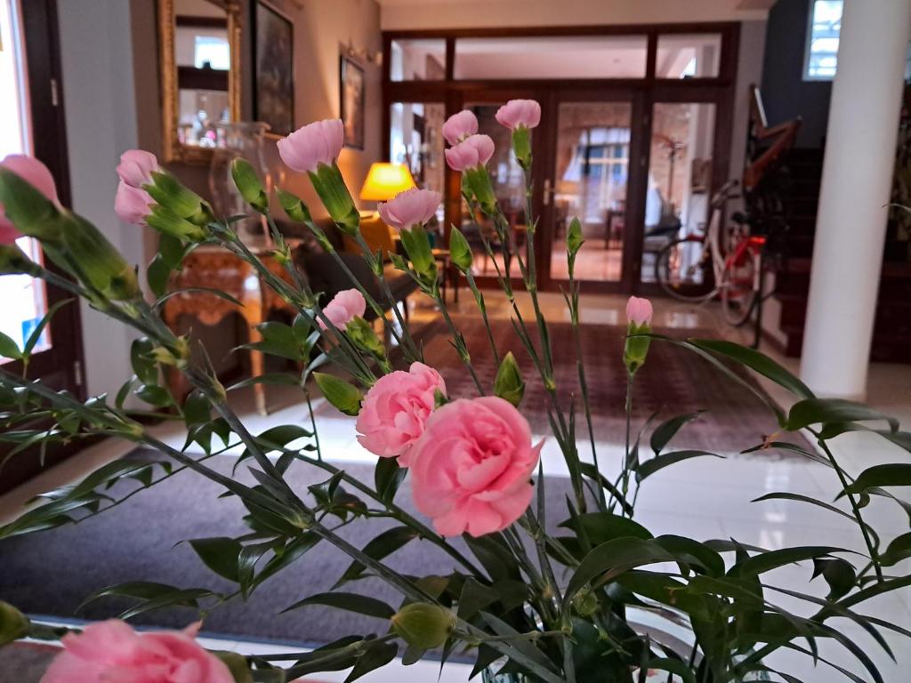 un jarrón lleno de flores rosas en una habitación en Hotel Stare Miasto Old Town, en Poznan